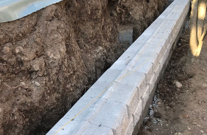 Posa della prima fila di blocchi prefabbricati in uno scavo per muro di sostegno