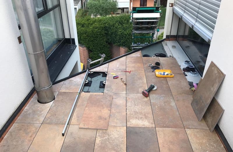 Posa di piastrelle in gres su terrazzo esterno con sistema di sollevamento, lavori in corso